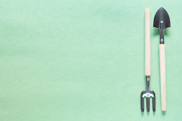 Gardening at home. Growing food in the garden, Fazenda. Shovel, rake, tools. Copyspace for text, top view. Flatlay on a green background.