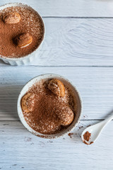 Top view of a delicious tiramisu dessert with cocoa and savoyardi cookies on gray background. Vertical photo