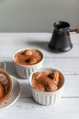 Delicious classic tiramisu in a jar on a gray background.