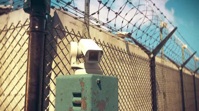 Closeup of CCTV camera in a heavily guarded place with barbed wire fence, prison