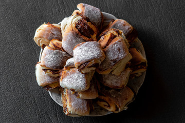 slide of fresh homemade buns with condensed milk and powdered sugar on a plate, on a gray background