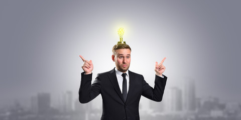 Businessman with a light bulb over his head and points his hands up on a gray background with a copy space. Business concept idea and innovation.