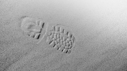 footprint with tread shoes on a sandy surface, monochrome
