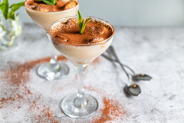 Classic tiramisu decorated with blueberries and mint in a glass on a grey background. Copy space.