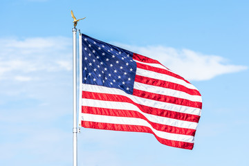 American flag is flowing in the wind on blue sky background.