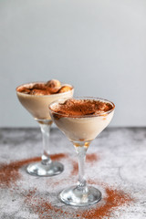 Tiramisu, traditional Italian dessert in glass on a grey stone background.