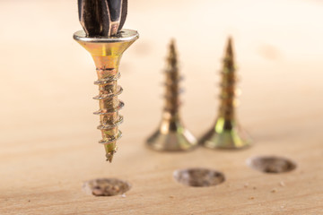 Screwing metal screws into chipboard for furniture construction. Small carpentry work in the home workshop.