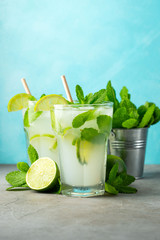Two homemade lemonade or mojito cocktail with lime, mint and ice cubes in a glass on a light stone table. Fresh summer drink.