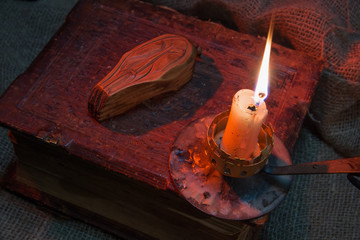 Big old book. The magical attribute lies on the book. The candle is burning. The concept of occult...