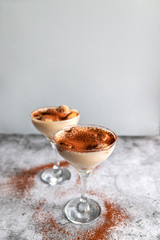 Close up of traditional Italian sweet tiramisu cake dessert in glass on grey background. Copy space.