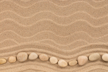 Fototapeta na wymiar Wavy line made of white stones lying on the sand of a beach. Top view.