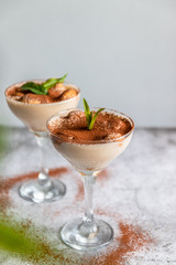 Tiramisu, traditional Italian dessert in glass on a grey stone background. Vertical