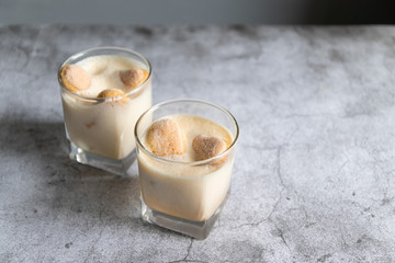 Close up of a traditional Italian sweet tiramisu cake dessert in glass on grey background.