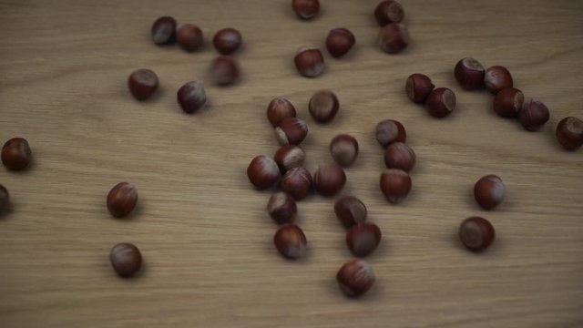 Organic hazelnut falling on wooden background. Slow motion.