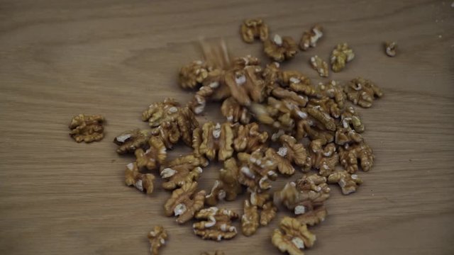 Organic Walnut kernel falling on wooden background. Slow motion.