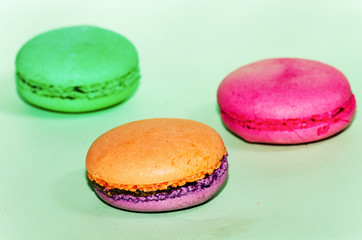 Delicious three multicolored macaroon on a green background
