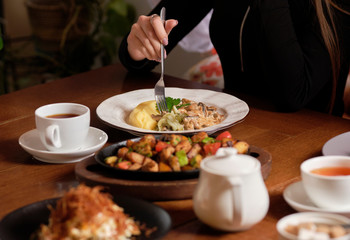 Female hands holding fork and knife, close Up. Woman eating business lunch, dinner at restaurant.
