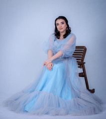 Fototapeta premium young beautiful model in the image of princesse ,cinderella dressed in a blue dress,sitting on a chair
