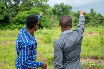 two young african business men, surveying a piece of land