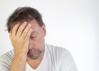 Middle-aged man with white T-shirt and quarantined boredom. Altered concentration and tiredness at home office.