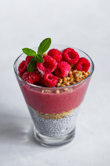 Fresh healthy dessert of Chia seeds raspberry puree banana and muesli in a glass