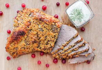 Meat roast beef cooked from beef tenderloin in mustard seeds and decorated with cranberries. Served...