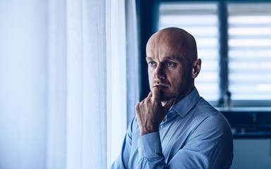 Worried depressed man looking throught the window.