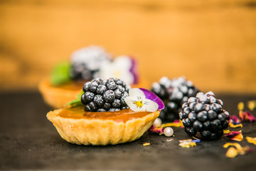 Sweet dessert Tartlets with fresh blackberry and delicious cream. Closeup