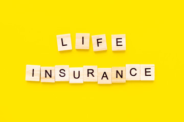 words life insurance. Wooden blocks with lettering on top of yellow background. insurance concepts.