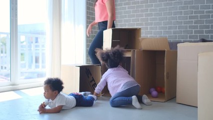 African American children play with boxes or carton in living room while their mother look busy to take care kids. Concept of happiness lifestyle for stay at home during covid virus pandemic. - Powered by Adobe