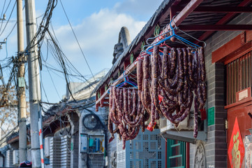 Homemade sausage hung on a hanger under the roof of the house, on the street.