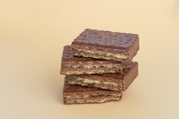 A pyramid of pieces of a chocolate bar on a light background. Chocolate waffles close up.