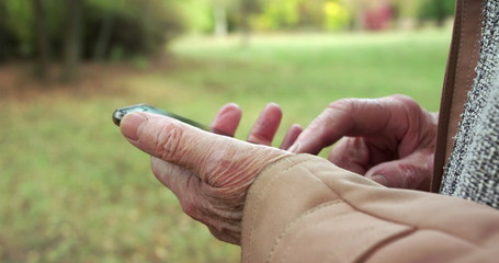Close view of tired, wrinkled male hands holding smartphone and typing at camera
