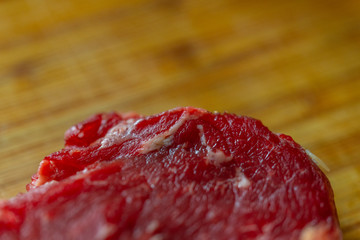 Shots of a sliced raw  fresh rump steak with fat on the steak on a wooden board