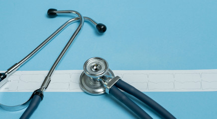 Stethoscope and cardiogram results on blue background.