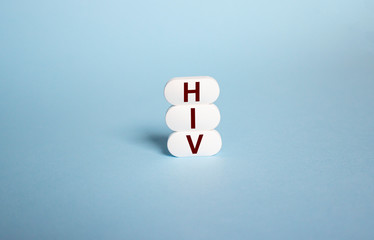 The inscription HIV on white tablets on a blue background. HIV disease concept.