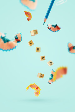 Creative back to school background with flying pencil shavings, wooden letter seals on a blue background with space for messages. © PINKASEVICH