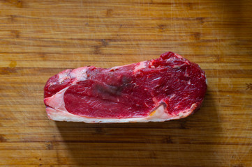 Shots of a sliced raw  fresh rump steak with fat on the steak on a wooden board
