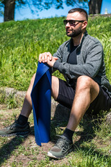 Naklejka na ściany i meble Sporting happy active bearded man holding blue exercise or yoga mat. Sportsman with fitness yoga carpets. Energetic for sportsmen. Like sports.