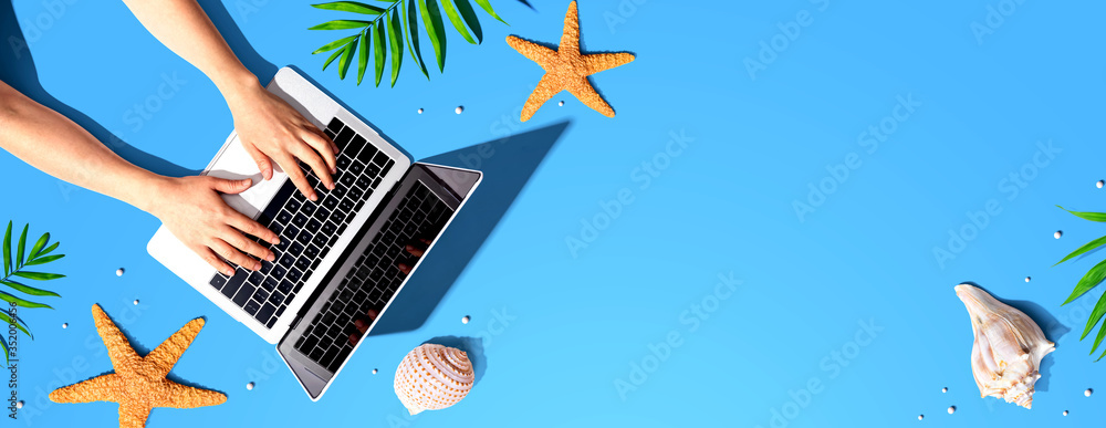Poster person using a laptop computer with summer theme objects - flat lay