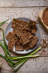 Loaves of flax green buckwheat and onion on a gray platter and a wooden table