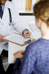 Female doctor and male patient discussing current health examination while sitting in clinic, close-up. Medicine concept