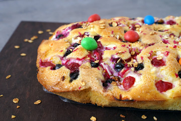 sponge cake with cherries, blueberries and  glazed nuts on the table close up