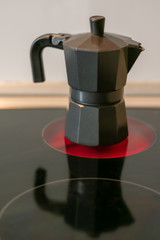 Coffee maker on a ceramic hob fire with the reflection in the glass