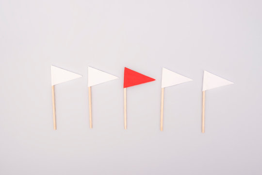 Red Paper Flag Among White Ones On Gray Background. Business Concept.