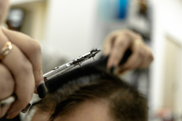 the man sits and he is cut. a man's haircut. women's hands of a hairdresser. scissors, comb, hair. neat haircut. process of trimming a person.