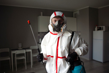 Portrait of a worker in a protective suit and equipment on the background of the apartment, a sanitary service man indoors