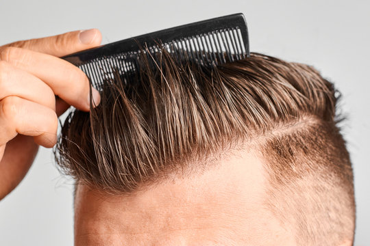 Man combing his clean hair with plastic comb. Hair styling at home. Concept of hair loss or or dandruff