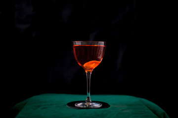 red cocktail in nick and nora glass on black background
