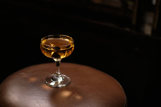 manhattan cocktail in bar with brack cherry on brown background